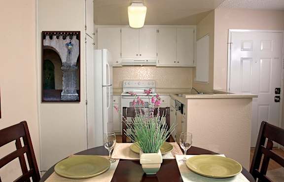 A kitchen with a table set for two with green plates.