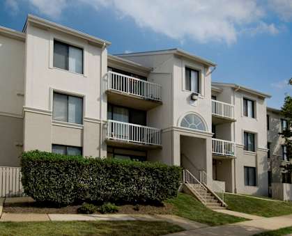 Apartment building with a green hedge in front.
