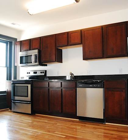 an empty kitchen with stainless steel appliances and wooden cabinets