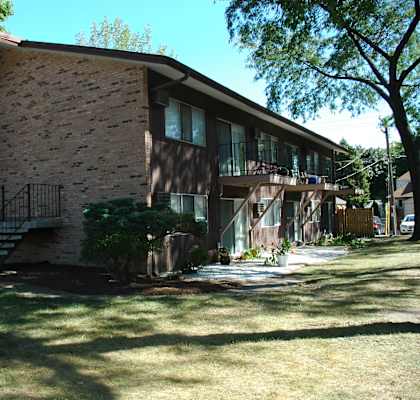 A brown house with a red door and a balcony.