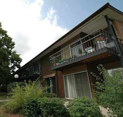A building with a balcony and a tree in front of it.
