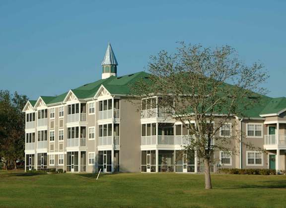 a large building with a green roof and a tree in front of it at Audubon Oaks, Lakeland, FL