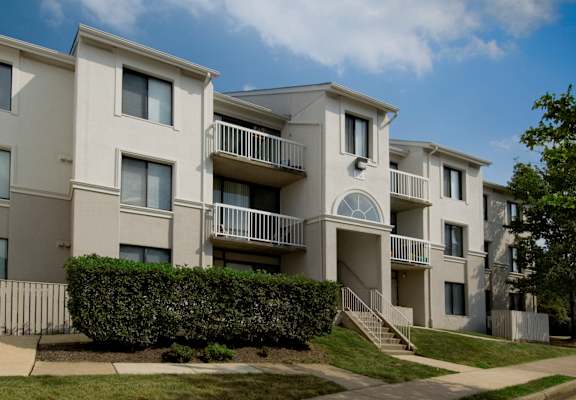 Apartment building with a green hedge in front.