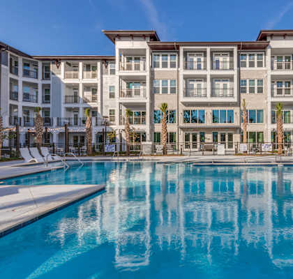 A large swimming pool in front of a multi-story apartment building.