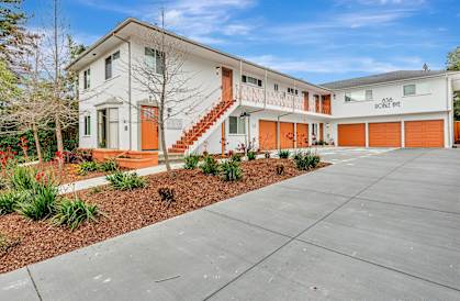 A white building with orange stairs and a red door.