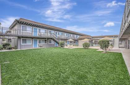 the backyard of a condo building with green grass and a lawn