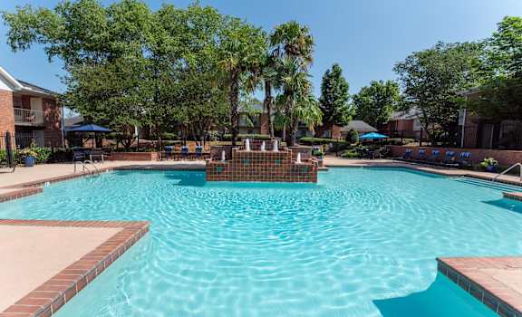 A swimming pool surrounded by trees and a fence.