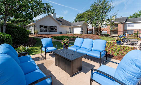 a patio with blue chairs and a table in front of a house