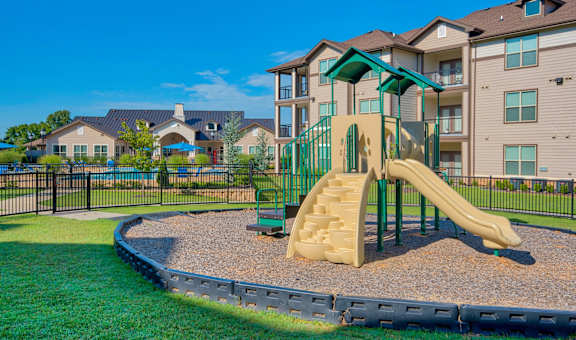 a playground with a slide in front of an apartment building