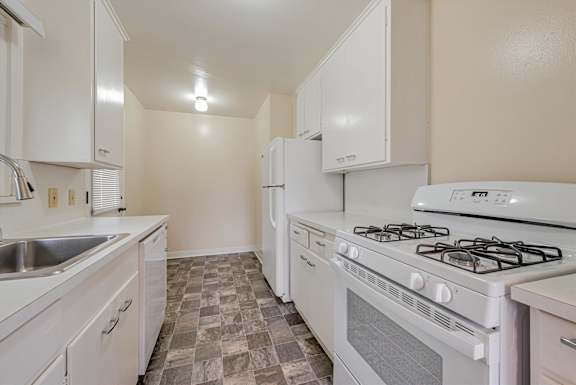 A kitchen with white appliances and a tiled floor.