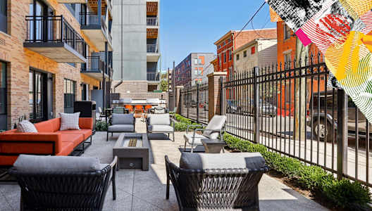 A patio with a black metal fence and a black wicker chair.