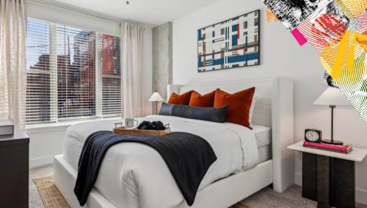 A bedroom with a white bed and a colorful abstract painting on the wall.