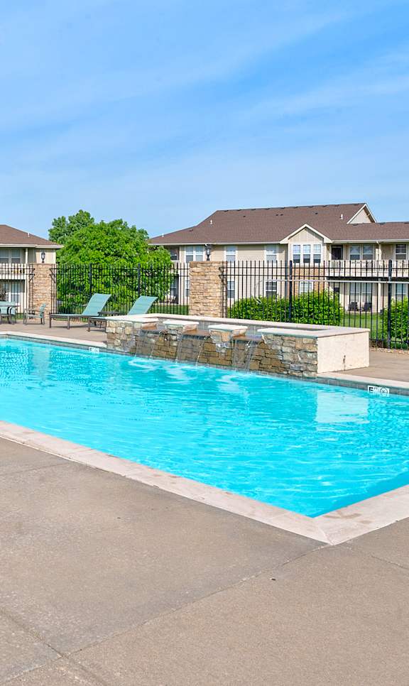 A swimming pool surrounded by a patio with chairs and umbrellas.