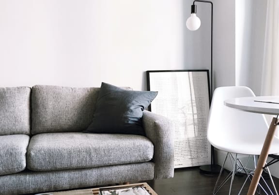 a living room with a gray couch and a white table and chair