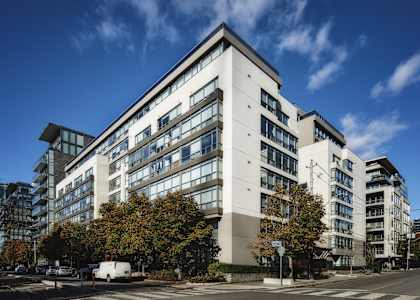 A large white building with a lot of windows and trees in front of it.
