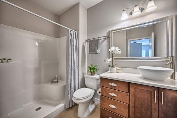 A white toilet sits in a bathroom with a white sink and a large mirror.