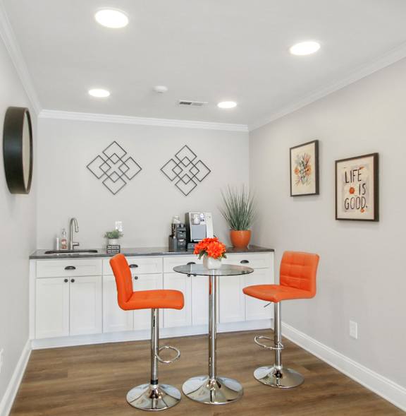 A kitchen with a white counter and orange chairs.