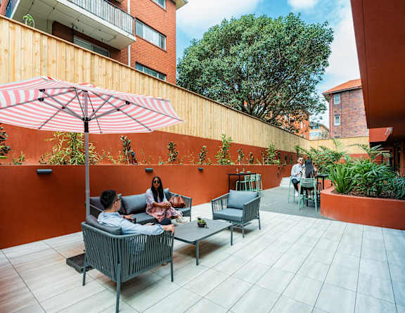 a group of people sitting on a patio with an umbrella