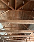 A wooden beam ceiling with a white pipe running through it.