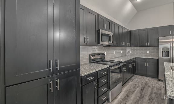 a kitchen with black cabinets and granite counter tops