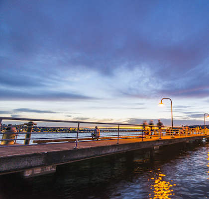 people walking on a pier at sunset on the water