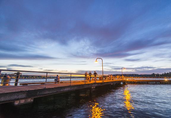 people walking on a pier at sunset on the water
