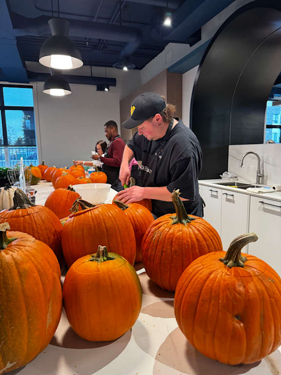 A man is carving pumpkins in a kitchen.