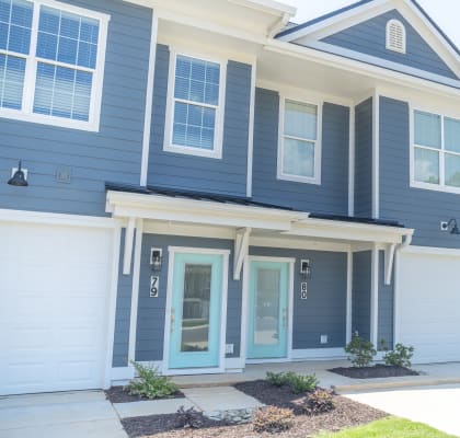 a house with blue siding and white garage doors at Landon Green Artisan Cottages Apartments, North Carolina, 28601