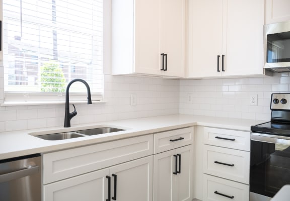 a kitchen with white cabinets and a large window at Landon Green Artisan Cottages Apartments, North Carolina, 28601