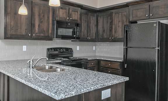A kitchen with black cabinets and a granite countertop.