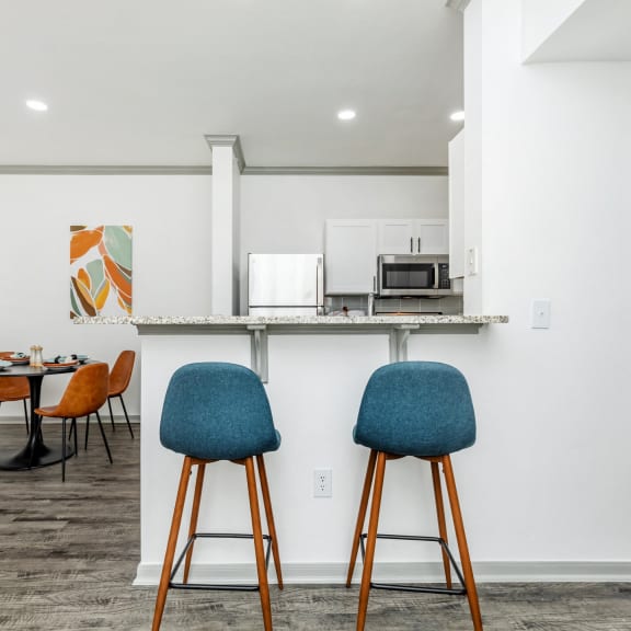 a kitchen and dining area with chairs and a counter with a microwave