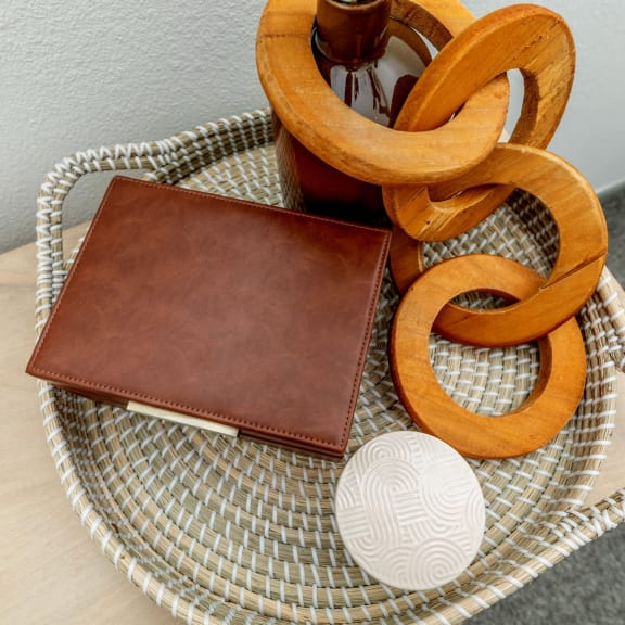 a leather wallet sitting on a table next to a rattan tray