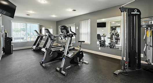 A gym with a row of exercise bikes and a weight rack.
