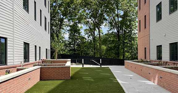 A grassy courtyard is surrounded by two buildings.