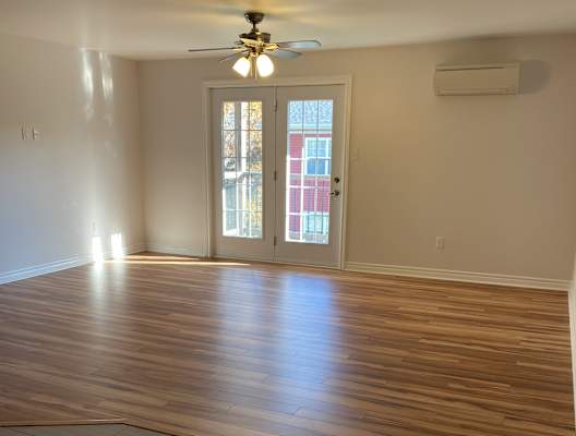 an empty living room with wooden floors and a ceiling fan