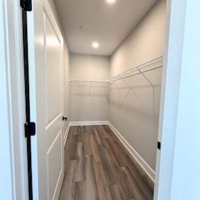 A hallway with white walls and wood flooring.