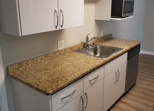 a kitchen with white cabinets and a cork countertop