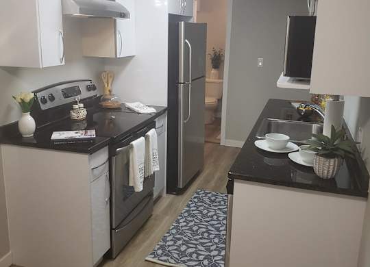 A modern kitchen with a black counter top and white appliances.