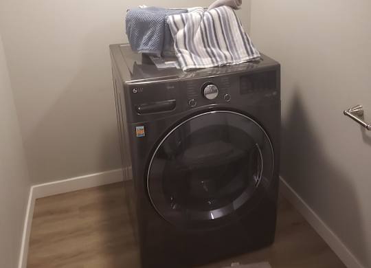 A black washing machine with a striped shirt hanging on it.