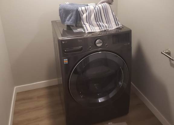A black washing machine with a striped shirt hanging on it.