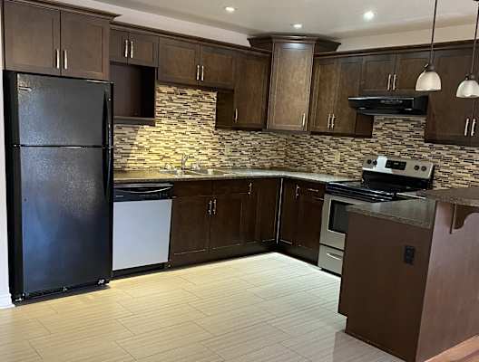 a kitchen with wooden cabinets and a black refrigerator