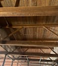 A wooden beam structure with a brown wooden ceiling.