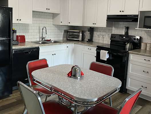 a kitchen with white cabinets and black appliances and a table with red chairs