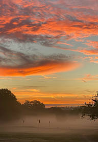 A beautiful sunset with a golf course in the foreground.