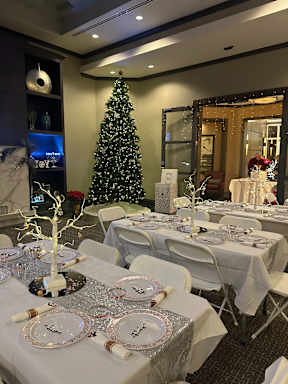 A Christmas tree stands in a room with tables set for a party.