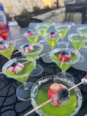 a bunch of martinis with olives on sticks on a table