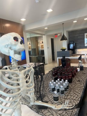 a skeleton standing next to a table of desserts in a hotel room
