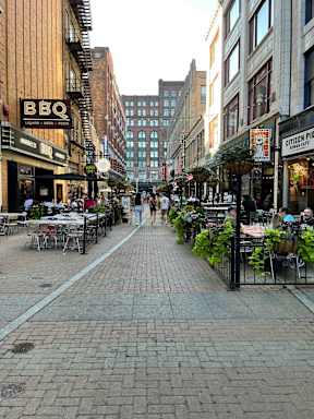 a city street with people walking and tables and chairs