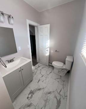 A bathroom with a sink, toilet and a mirror.