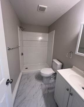 A white toilet is in a small bathroom with a white sink.